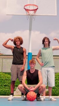 vertical Multicultural male friends posing together on a basketball court