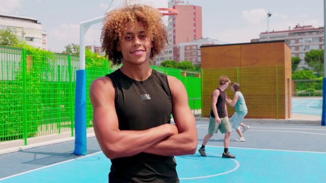 Young smiling basketball player standing on an outdoor court