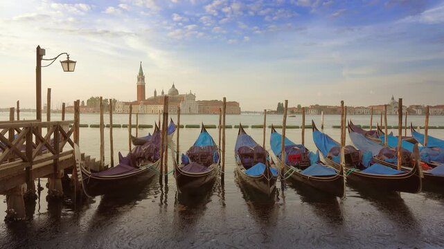 View of gondolas moored at the waterfront with the San Giorgio Maggiore church in the background in Venice, Veneto, Italy.
