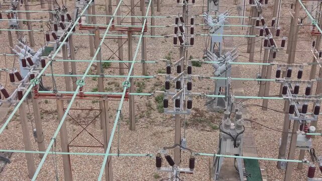 Top-down aerial drone video footage of a modern electrical power substation showing industrial high voltage equipment, grid infrastructure, and multiple transformers operating outdoors