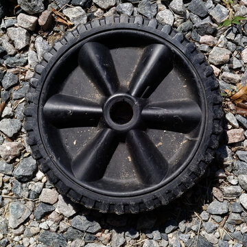 Black Plastic Wheel on Gravel Surface
