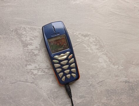 Close up of an old Nokia 3510i phone charging on a gray table.
