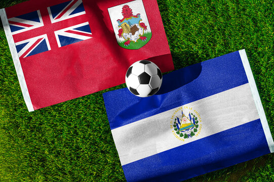 Bermuda vs. El Salvador football match. National flags on green grass with soccer ball in the middle. Football background for international match.