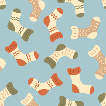 Vector hand drawn seamless pattern with cozy knitted socks in warm retro colors on blue background. Cute winter clothing texture for textile, fabric, wrapping paper, wallpaper, seasonal print