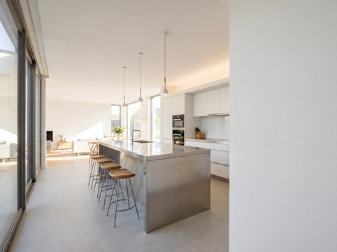 Stainless Steel Kitchen Island with Wooden Bar Stools in Bright Modern Minimalist Interior