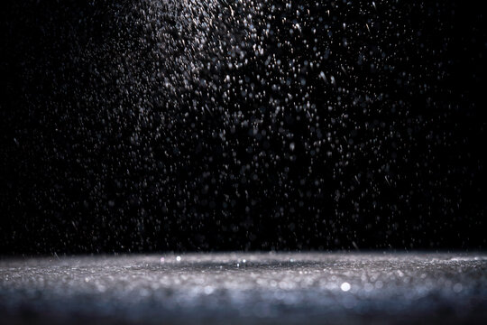 Water droplets fall in a dark space creating a pattern of light and shadow during a moment of stillness