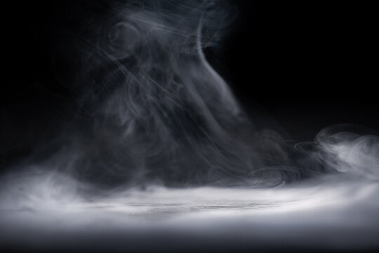 Smoke rising in the dark with an unclear shape forming, creating an abstract scene in a minimal light setting