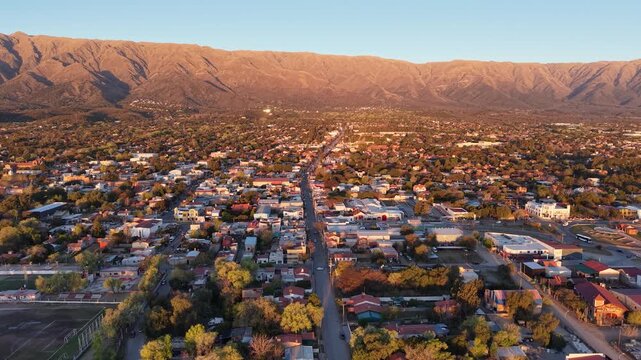 Aerial stock footage of Villa de Merlo main avenue facing Comechingones mountains at golden hour
