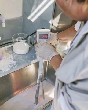 Digital ph probe measuring a pale slurry in a food technology lab, showing a precise reading for quality control and product development