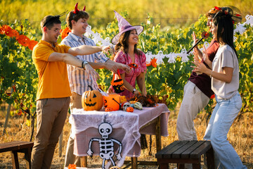 Obraz premium Young people in Halloween costumes reaching out towards each other at a vineyard celebration