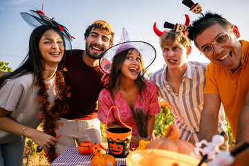 Obraz premium Joyful friends wearing Halloween accessories posing with funny faces close to the camera during a vineyard party.