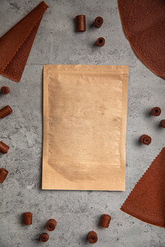 Natural fruit leather rolls and sheets arranged around craft paper ziplock pouch mock up on grey concrete background
