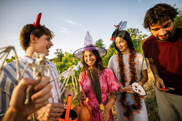 Obraz premium Young people looking at a skeleton bat prop during an outdoor Halloween celebration.