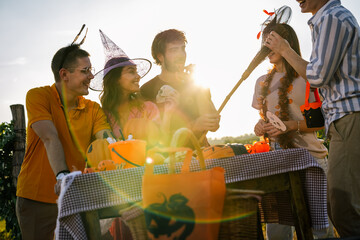 Obraz premium Friends wearing Halloween costumes enjoying sunset light at an outdoor vineyard party.