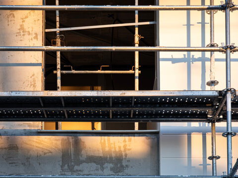 Warm sunlight shines on scaffolding in front of an unfinished building during sunset