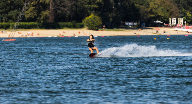 Female wakeboarder wakesurfing. Girl riding waterski cabel. Holding tow rope. Summer activities in the lake.
