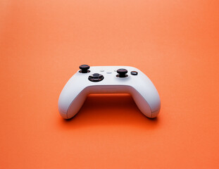 White Wireless Game Controller on Bright Orange Background © stokkete