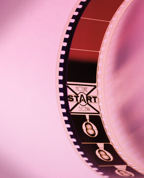 Curved 35mm Film Leader with Picture Start Mark on Pink Background
