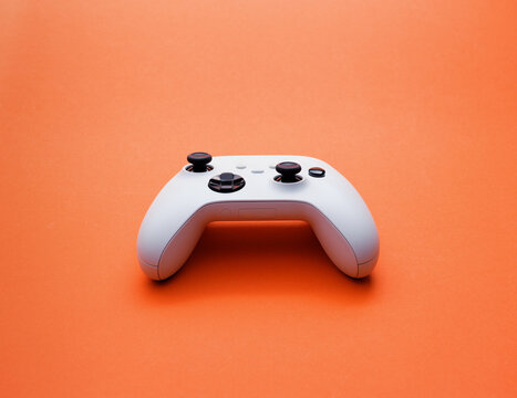 White Wireless Game Controller on Bright Orange Background