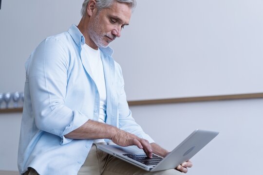 Portrait of happy 40s freelancer man using laptop computer at home office