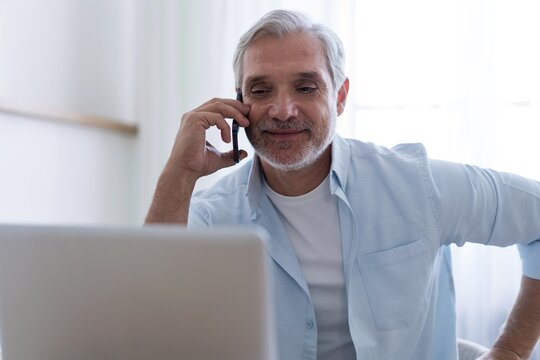 Busy mature business man talking on mobile phone in office