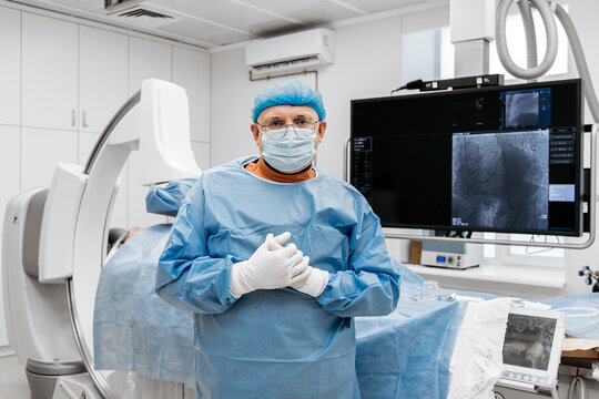 Interventional cardiologist posing near angiography equipment in a medical setting. Concept cardiovascular medicine, cardiac diagnostics and interventional cardiology.