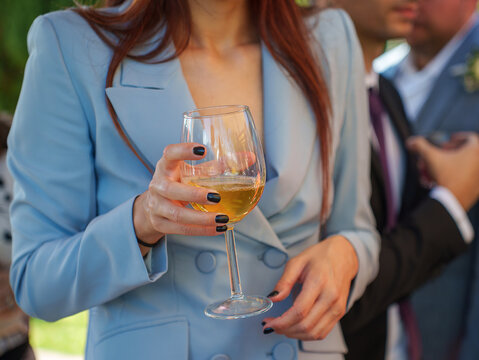 Donna elegante in completo azzurro che tiene un calice di vino durante un evento sociale