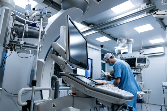 Doctor working beside a patient in a high-tech operating room equipped with ultrasound and monitoring systems.