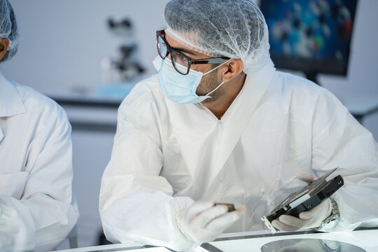 A team of researchers collaborates inside a laboratory, carefully examining computer hardware components to solve technical problems, driven by focus and teamwork.