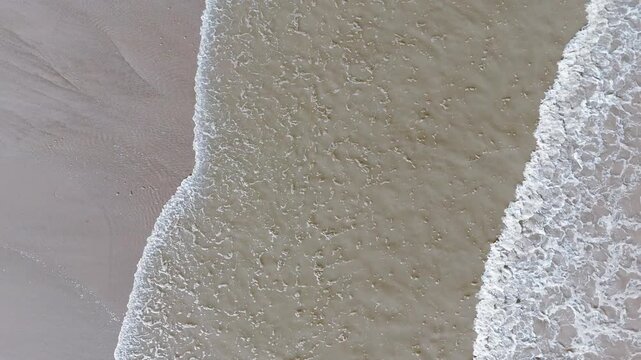 Soft waves curling onto pale sand