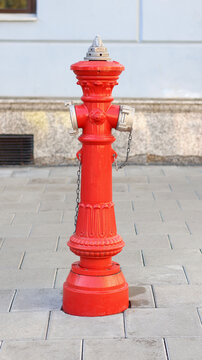 Red fire hydrant on city street. Vintage style public water supply for firefighting.