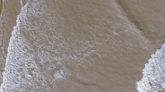 Waves crash onto sandy shore with gentle foam