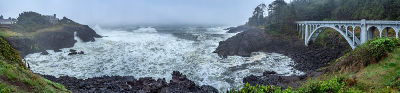 Beautiful wide panoramic view of a historic concrete arched bridge on a stormy misty ocean coast