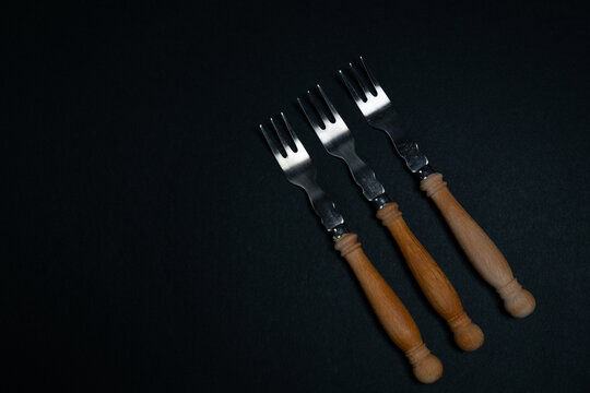 Wooden handled metal forks arranged on dark background