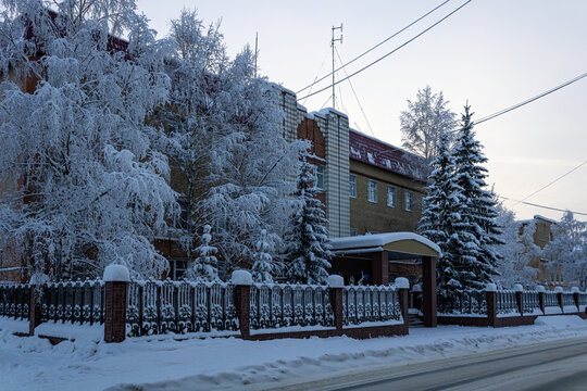 The building of Federal Security Service in Ukhta, Komi Republic, Russia behind snow-covered trees and road.
