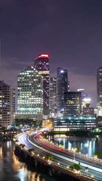 Night time lapse of traffic going over a Brickell Key Bridge and the tall buildings of Miami Florida. Vertical video.