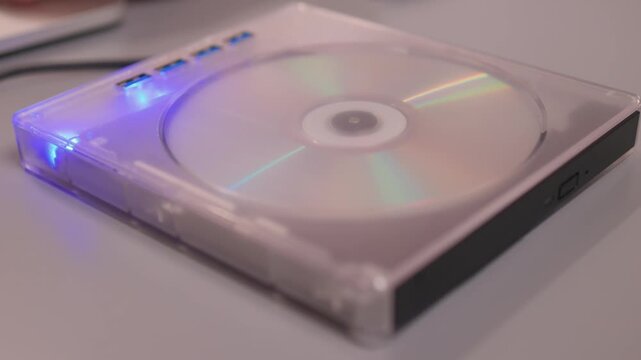 Close examination of fingers setting up DVD player with spinning disc. Focused shot of hands configuring compact DVD device with illuminated light and rotating disc