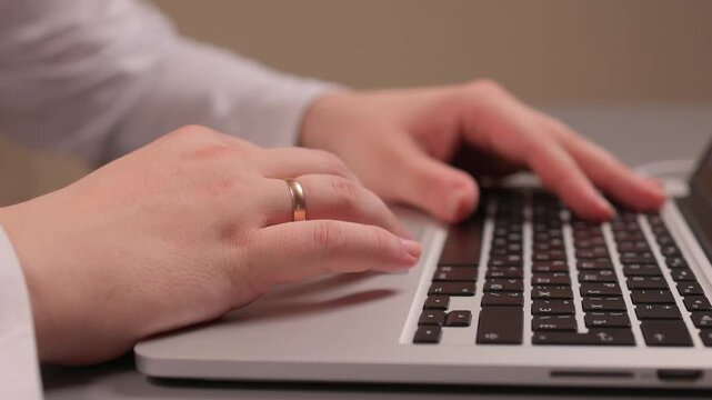 Coding hands work. Person in white sleeve entering commands on silver device. Detailed shot of hands typing code on modern laptop illuminated by soft studio lighting