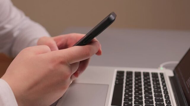 Multitasking at desk. Professional reviewing multiple devices. Focus on work involving multiple gadgets. Closeup of individual managing messages and coding tasks simultaneously