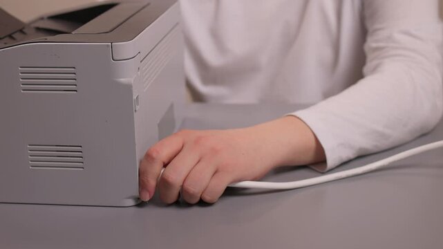 Hands connecting printer. Plugging in printer cable steps. Closeup of hands connecting printer cable carefully. Detailed tutorial demonstrating printer setup on neutral workspace