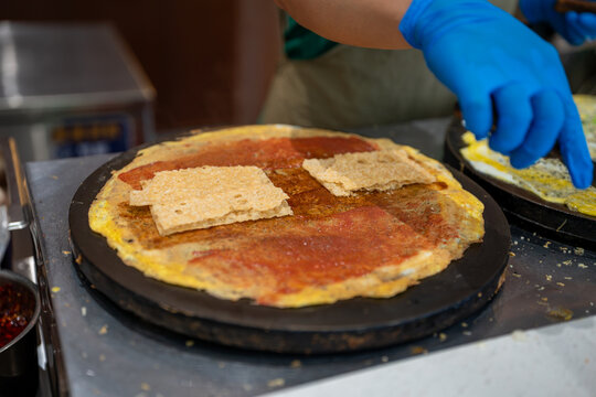 A vendor handles flatbread on a hot griddle, with prepared pieces resting on the browned bread.