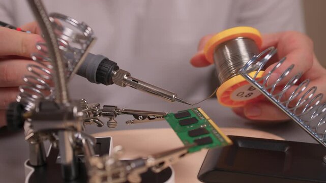 Skilled technician connecting electronic components. Professional electronics technician meticulously soldering components on printed circuit board using specialized tools