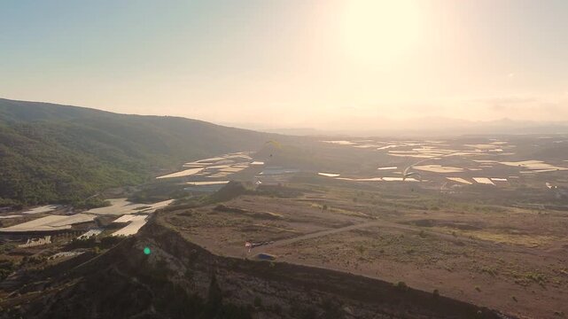 Epic Cinematic Drone View of Two Powered Paragliders Flying Over Dramatic Mountain Landscape at Sunset