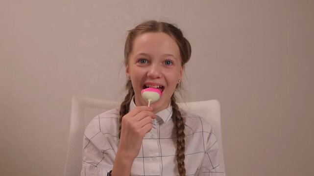 Girl sampling vibrant candy joyfully. Youthful girl indulges in colorful treat happily. Child with braided hair tastes bright pink candy with curiosity and delight