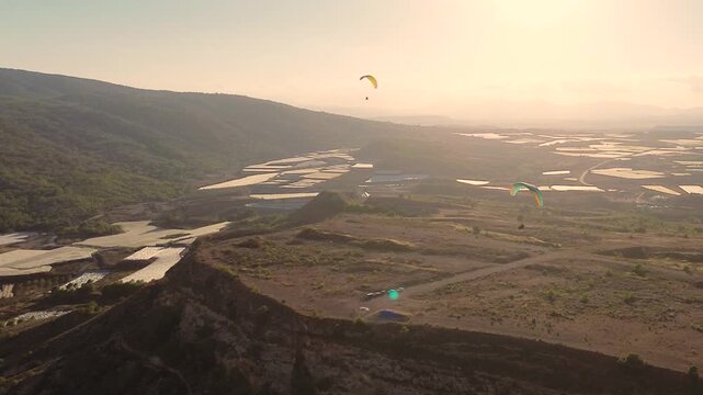 Epic Cinematic Drone View of Two Powered Paragliders Flying Over Dramatic Mountain Landscape at Sunset