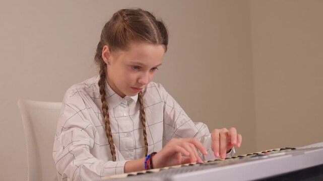 Young female musician rehearsing melodies on digital piano at home. Brightly lit scene of youthful girl honing musical skills on electronic keyboard in cozy environment
