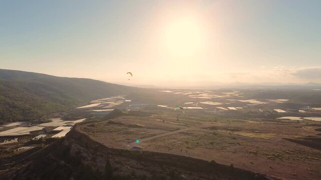 Epic Cinematic Drone View of Two Powered Paragliders Flying Over Dramatic Mountain Landscape at Sunset
