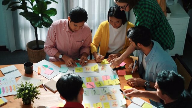 Close up of professional business team hands writing and putting sticky note on scrum task board. Top view of project manager write task and use kanban board to manage time and workflow. Convocation.