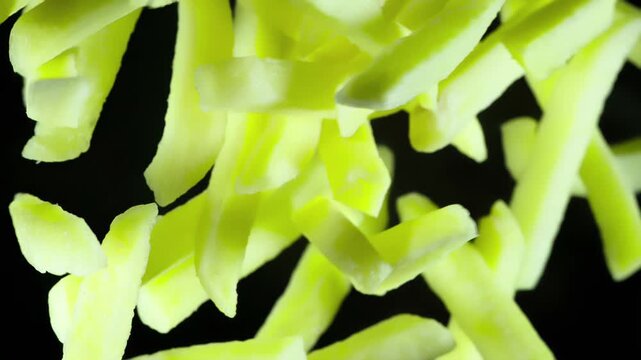 Sliced Fried Potatoes. Fries thrown up into the lens on a black background. pieces hang in the air and gradually disappear in the dark