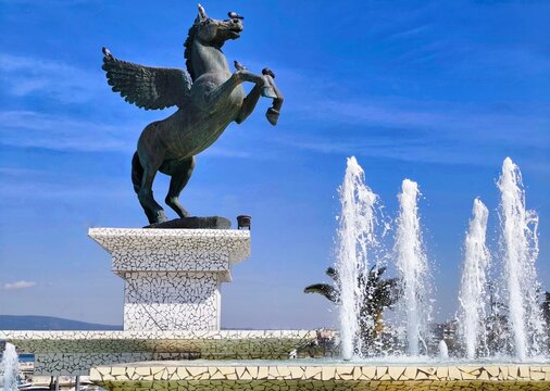 Photo of the Pegasus statue in Eleftherios Venizelos square, a picturesque seafront public space at the end of Ethnikis Antistaseos sreet in the modern city of Corinth, Greece.
